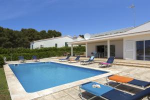 a swimming pool with chairs and a house at Villa Lola in Santo Tomás