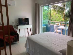 a bedroom with a bed and a television and a window at Pousada Vitória in Ilhéus