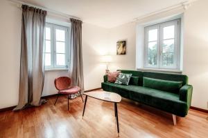 a living room with a green couch and two windows at Salorino Apartments by Quokka 360 - Quiet Escape with Panoramic Nature Views in Mendrisio
