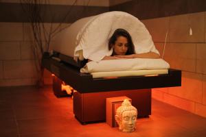 Una donna sdraiata in un letto con una maschera di Hotel & Spa Marina d'Adelphia ad Aix-les-Bains