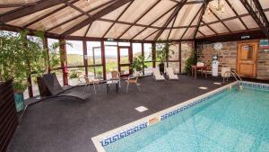 a swimming pool with a patio area with chairs and umbrellas at Leeming Wells in Haworth