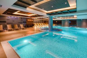 a large swimming pool in a building with chairs at Gorski Hotel & Spa in Kopaonik