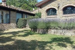 una casa con un muro di pietra e alcuni cespugli di Villa Pianelli ad Arezzo