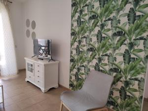 a room with a chair and a tv on a dresser at APARTMENT LA CALA DESIGN & ALAMAR SEA WIEW. in La Cala de Mijas