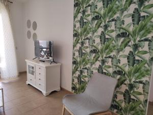 a room with a chair and a tv on a dresser at APARTMENT LA CALA DESIGN & ALAMAR SEA WIEW. in La Cala de Mijas