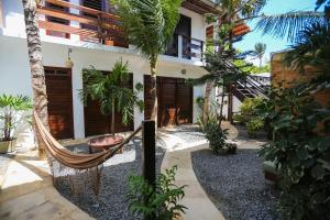 a hammock in front of a house with palm trees at Mandala Hostel Jeri in Jericoacoara