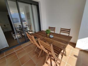 une table en bois avec des chaises et une plante en pot. dans l'établissement APARTMENT LA CALA DESIGN & ALAMAR SEA WIEW., à La Cala de Mijas