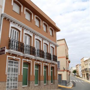 - un bâtiment avec des portes et des balcons verts dans une rue dans l'établissement Hostal Avenida, à Tabernas