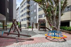 a playground with a swing set and a tree at PALMEIRAS A14 in Ubatuba