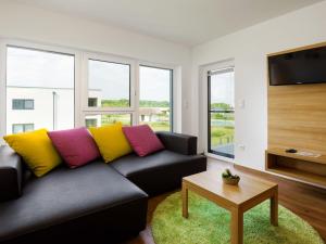 a living room with a black couch with colorful pillows at Heritage Apartment in Lutzmannsburg with Swimming Pond in Zsira