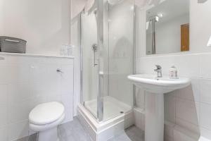 a white bathroom with a shower and a toilet and a sink at JKG Property Solutions Presents Cosy City Apartment in Coventry