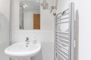uma casa de banho branca com um lavatório e um espelho em JKG Property Solutions Presents Cosy City Apartment em Coventry