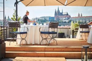 a man standing at a table on a deck with chairs at Four Seasons Hotel Prague in Prague