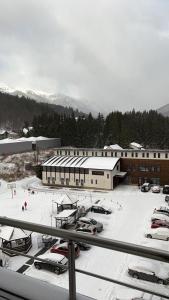 un aparcamiento cubierto de nieve frente a un edificio en Coca Apart Mountain View, en Sinaia