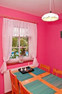 a pink dining room with a table and a window at Chata Dvě Sestry in Červená Voda