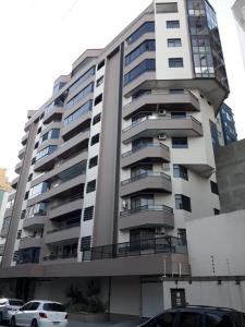 - un grand immeuble avec des voitures garées devant dans l'établissement Apartamento Meia Praia Itapema, à Itapema