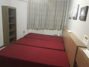 une chambre avec un lit rouge avec une fenêtre dans l'établissement Apartamento Meia Praia Itapema, à Itapema