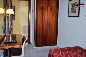 Habitación con puerta de madera, mesa y escritorio. en Hotel Aragón, en Salamanca
