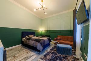 a bedroom with green walls and a bed and a chair at Cozy modern space at the heart of the city in Debrecen