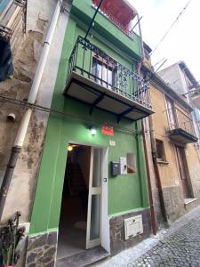 a green building with a balcony and a door at B&B Casetta Verde FELICE in Scilla