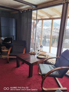 a living room with a table and chairs and a television at Cabanuta din munti in Moieciu de Jos