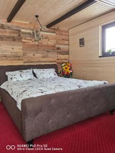 a large bed in a room with a wooden wall at Cabanuta din munti in Moieciu de Jos