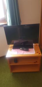 Un televisor sobre un soporte de madera con un control remoto encima. en Residence Hotel 4s Montagna, en Cogolo