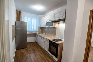 cocina con armarios blancos y nevera de acero inoxidable en Apartament 3 camere Royal Brasov en Brasov
