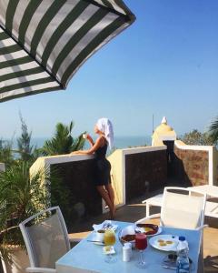 a woman standing on a balcony with a table with food at Fort Tiracol Heritage Hotel in Arambol