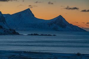 a group of mountains in the ocean at sunset at Feriehus med flott havutsikt ved Hauklandstranden in Leknes