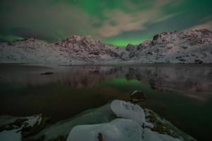 a view of the northern lights over a mountain at Feriehus med flott havutsikt ved Hauklandstranden in Leknes