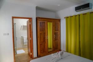 a bedroom with a green curtain and a mirror at Villa Charette-Self Catering Villas in La Digue