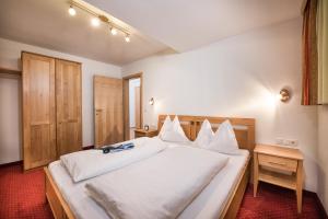 a bedroom with a large bed with white sheets at Appartements Salzburgerhof in Flachau