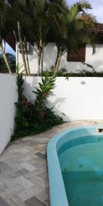a swimming pool next to a white wall with palm trees at Casa grande com piscina e churrasqueira in Florianópolis