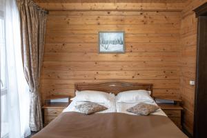1 dormitorio con 1 cama en una pared de madera en Altair Hotel, en Bukovel