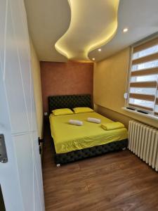 a bedroom with a bed with yellow sheets and a window at Brend new luxurious apartment in downtown with free parking in Novi Sad