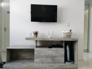 a living room with a tv on a wall at Studio à 500m da praia, AC e Vaga in Balneário Camboriú