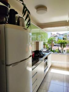 uma cozinha com um frigorífico branco e um fogão em Luminoso Studio BC, 500m da praia e Big Wheel!! em Balneário Camboriú