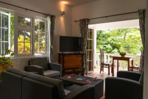 a living room with a flat screen tv and chairs at Villa Charette-Self Catering Villas in La Digue