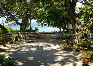 a park with a tree and a fence and the beach at Villa Charette-Self Catering Villas in La Digue