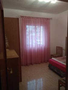 een slaapkamer met een bed en een raam met roze gordijnen bij Carniceria Alfath in Alicante