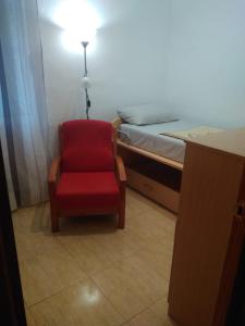 een kamer met een rode stoel en een bed bij Carniceria Alfath in Alicante