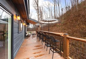 una terraza de madera con sillas y sombrilla en Night Owl cabin en Gatlinburg