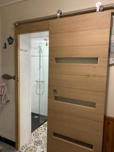 a wooden door in a bathroom with a shower at Maison de vacances Arzaël à 200m de la plage célèbre de Mr Hulot in Saint-Nazaire