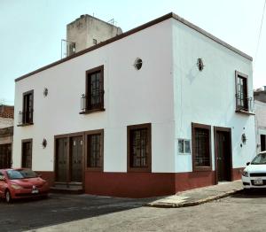 a white building with a red car parked in front of it at Suites del Centro in Morelia