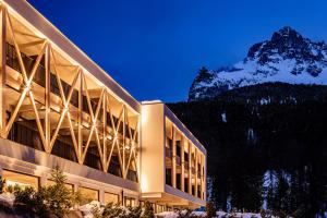 a large building with a mountain in the background at Sporthotel Obereggen in Obereggen