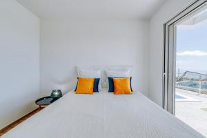 a bedroom with a bed with orange pillows and a window at Casa das Voltinhas in Ponta do Sol +31 photos