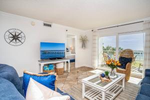 a living room with a blue couch and a tv at Islander 203 - Dances with Dolphins in Destin