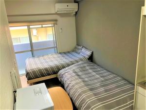 2 letti in una camera con scrivania e computer portatile di Hotel PEACE PARK Tokaichi - Vacation STAY 95320v a Hiroshima