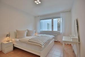 een witte slaapkamer met een bed en een raam bij Domizil Strandallee 30 Domizil Strandallee 30 Appartement 28 in Timmendorfer Strand